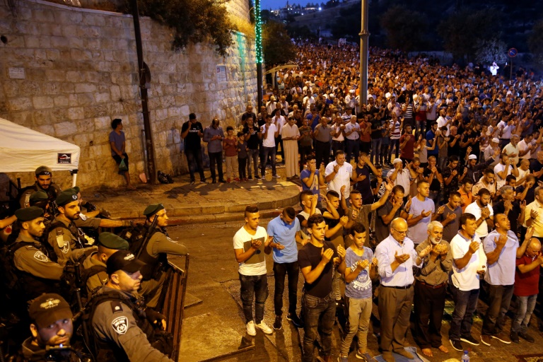 Des forces de sécurité israéliennes regardent des Palestiniens prier à l'extérieur de l'esplanade des Mosquées à Jérusalem, le 24 juillet 2017 / © AFP / Ahmad GHARABLI