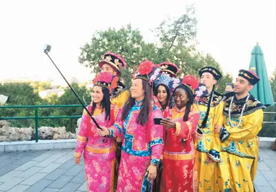 Foreigners in ancient Chinese royal dresses take selfies at Jingshan Park in Beijing. (People's Daily Overseas Editon/Gao Bing)