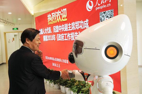 People’s Daily Online’s artificially intelligent robot Wangzai shakes hands with a guest at the two sessions. (Photo by Jiang Jianhua from People’s Daily Online)