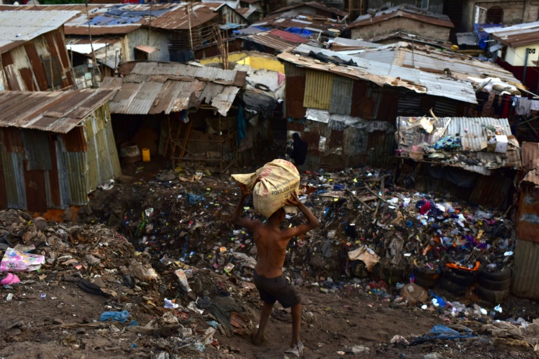 Un habitant d'un bidonville de Freetown transporte des objets récupérés dans une décharge, le 28 mars 2018 / © AFP/Archives / ISSOUF SANOGO