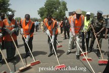 Le Président tchadien Idriss Déby prend l'initiatie de balayer la rue avec un balai, entouré de plusieurs collaborateurs.