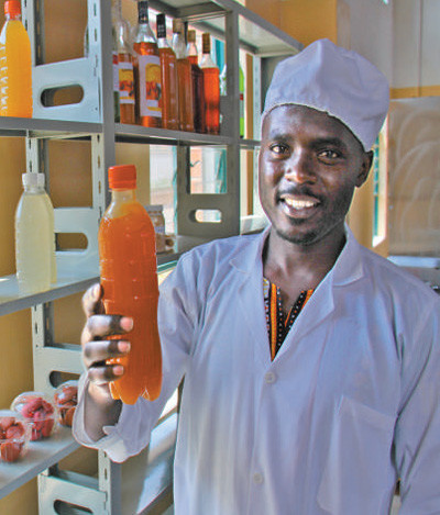 A student of China-aided Musanze Polytechnic shows the fruit wine made by him. (Photo by Wang Yunsong from People’s Daily)