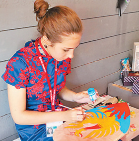 A woman in traditional Chinese costume paints at a shop in Vladivostok, Russia on Sept. 11, 2018. (Photo by Du Shangze from People’s Daily)