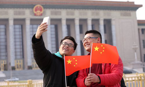 Visitors pose for a selfie with Chinese national flags in front of the Great Hall of the People in Beijing on Thursday. The hall will host several events at the annual two sessions, including the plenary meetings of China's top legislative body and political advisory body. (Photo: IC)
