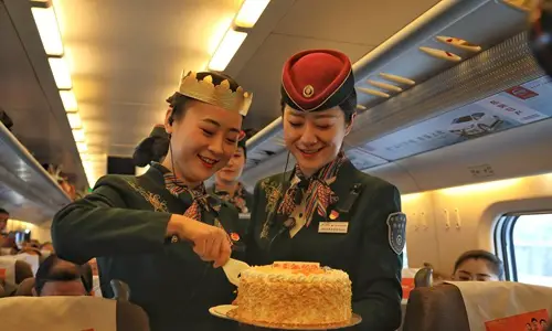 Attendants and passengers celebrate the fifth anniversay of the Lanzhou-Xinjiang high-speed railway over the weekend. The 1,776-km line transported 30.75 million passengers during the period. (Photo: Courtesy of China Railway)