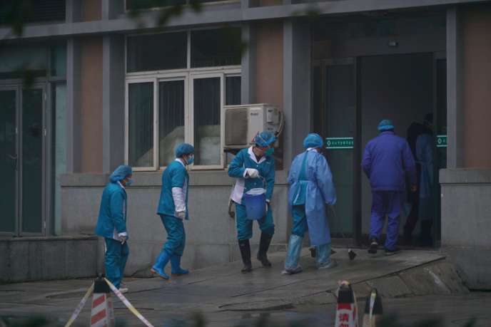 Des employés désinfectent l’entrée de l’hôpital de Wuhan, où des patients contaminés par le virus sont traités, le 22 janvier. DAKE KANG / AP