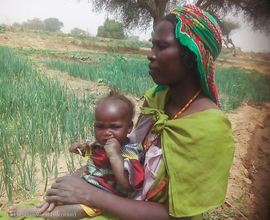 Fatima (un nom d’emprunt) tient sa fillette contre elle près du camp de réfugiés de Tolgo, au Tchad, en 2019. (© Lutheran World Federation) Fatima (un nom d’emprunt) tient sa fillette contre elle près du camp de réfugiés de Tolgo, au Tchad, en 2019. (© Lutheran World Federation)