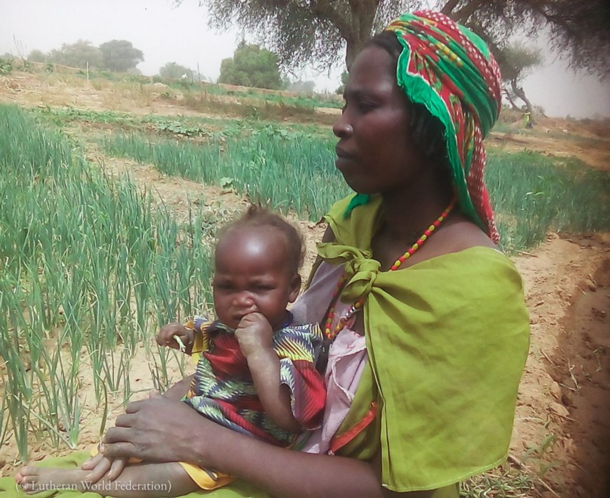 Fatima (un nom d’emprunt) tient sa fillette contre elle près du camp de réfugiés de Tolgo, au Tchad, en 2019. (© Lutheran World Federation)