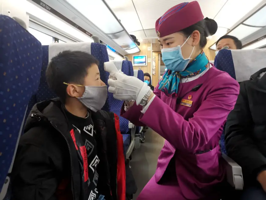 A train attendant takes body temperature of a boy on train D354 from Chengdu East Railway Station to Shanghai Hongqiao Railway Station, Feb.2, 2020. A travel rush is seen after the Spring Festival holiday. To contain the spreading of the novel coronavirus, the train attendants have to inspect train cabins on a regular basis, and observe passengers and ask if they have such symptoms as fever, cough and dyspnea, so as to ensure safe travels. By Hu Zhiqiang, People’s Daily Online