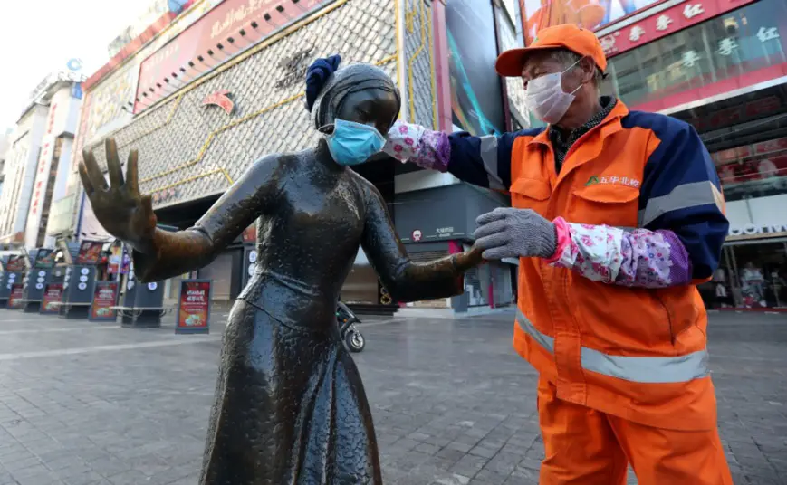 A sanitation worker puts a mask on a sculpture at a pedestrian mall in Kunming, capital of southwest China’s Yunnan province, to remind citizens to wear masks when they go out, Feb. 6, 2020. Photo by Yang Zheng/ People’s Daily Online