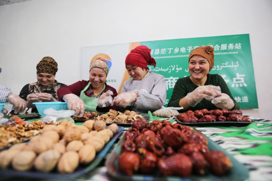 Villagers make a special snack with Chinese dates and walnuts in the e-commerce service center of Beidi village, Jinghe county, northwest China’s Xinjiang Uygur autonomous region. (Photo by Kuerbanjiang Mamuti/People’s Daily Online) Villagers make a special snack with Chinese dates and walnuts in the e-commerce service center of Beidi village, Jinghe county, northwest China’s Xinjiang Uygur autonomous region. (Photo by Kuerbanjiang Mamuti/People’s Daily Online)