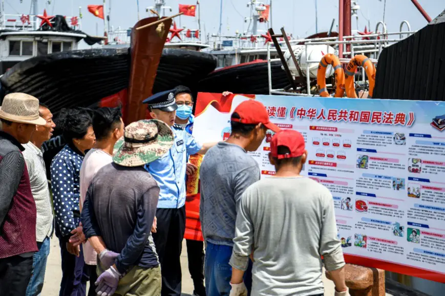 Citizens, a police officer and a grid-based community worker explains the civil code to fishermen and answer relevant legal problems in Dongying, east China’s Shandong province, June 4. Photo by Chen Jingxu/People’s Daily Online