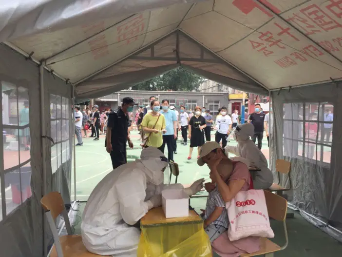 A medical worker samples throat swab for a kid at a nucleic acid testing station in Hepingli Qiqu community, Dongcheng district, Beijing, on June 23. Photo by Hu Qingming/People’s Daily Online