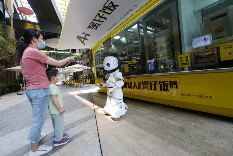 A mother and her son wait for food cooked by a robot in Zhengzhou, capital of Central China’s Henan Province on May 1. Photo by Zhang Tao/People’s Daily Online