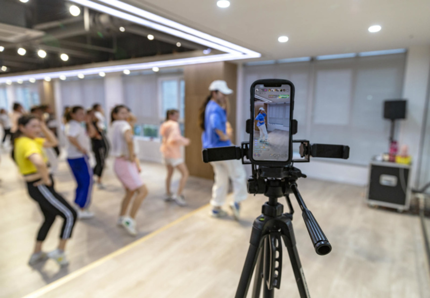 Trainees learn Zumba dance under the guidance of a fitness coach during a livestreaming show in a gym in Sihong county, Suqian, Jiangsu province, June 9. (Photo by Chen Yu/People’s Daily Online)