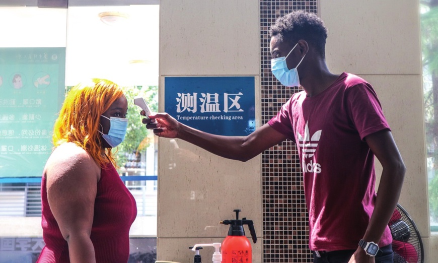 Barry (right), a college student at Central China Normal University from Gambia, checks a female student's body temperature on August 28, serving as an anti-epidemic volunteer. Photo: Courtesy of CCNU Barry (right), a college student at Central China Normal University from Gambia, checks a female student's body temperature on August 28, serving as an anti-epidemic volunteer. Photo: Courtesy of CCNU