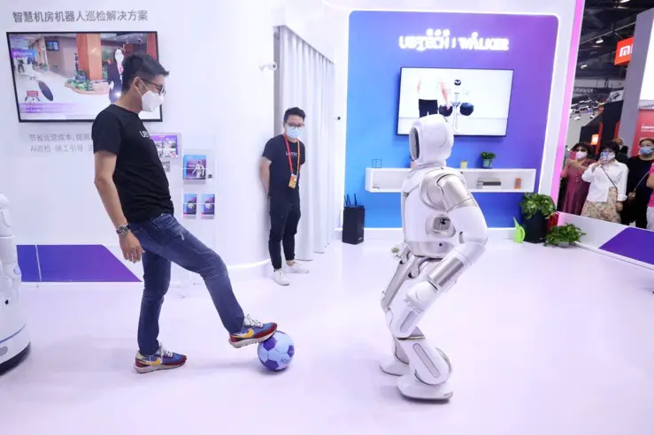A staff worker plays football with a robot in the comprehensive exhibition area of the 2020 China International Fair for Trade in Services (CIFTIS), September 6. (Photo by Chen Xiaogen/People’s Daily Online)