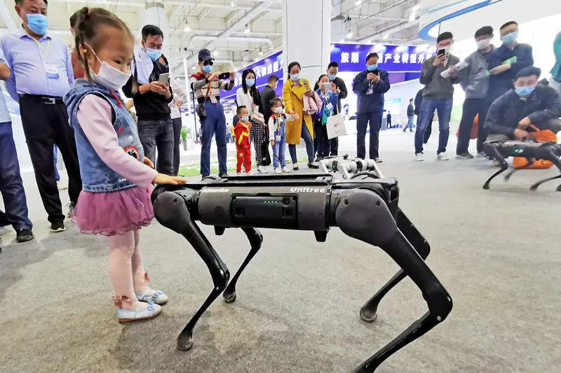 A girl interacts with a robot dog at the 22nd Dalian International Industry Fair held in Dalian, northeast China’s Liaoning province, October 11. (Photo by Liu Debin/People’s Daily Online)