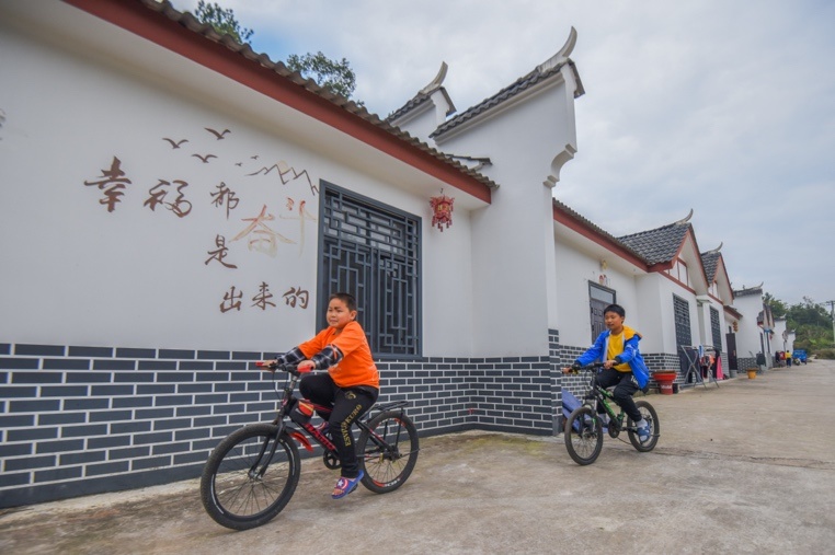 Children ride bikes in front of the houses in a resettlement site in Xiejiaping Tujia ethnic township, Songzi, central China's Hubei province, October 11. (Photo by Huang Zhigang/People's Daily Online)