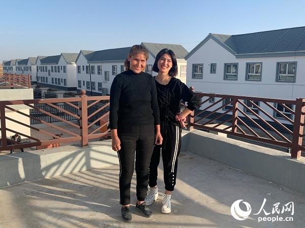 Kuwahan Mettursun and her daughter pose for photos in front of their new home. (Photo by Yang Rui/People’s Daily Online)