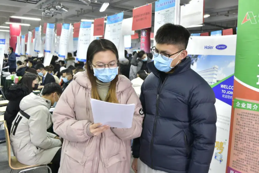 Two college graduates talk at a career fair on campus in east China’s Shandong province, Qingdao on Jan. 4. Photo by Han Hongshuo/People’s Daily Online