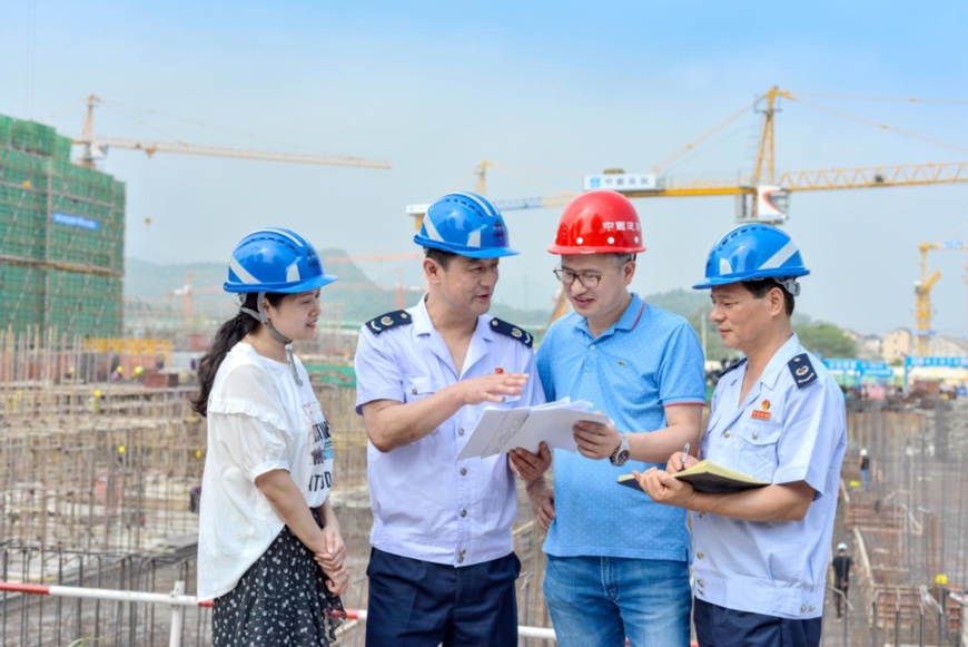 Staff members with the tax bureau of Changxing county, east China's Zhejiang province, interview construction workers to make sure they understand the country’s policies on cutting tax and administrative fees, Sept. 11, 2019. (Photo by Tan Yunfeng/People's Daily Online)