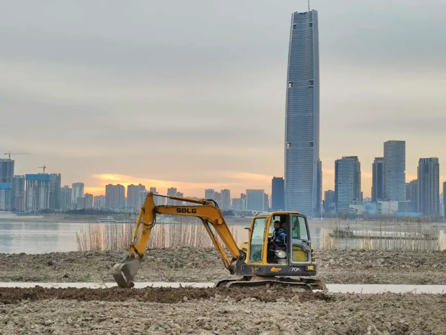 Photo taken on Jan. 9, 2021 shows an excavator removing sand and digging a ditch beside the Yangtze River in the Hankou waterfront in Wuhan, central China’s Hubei province. (Photo by Li Changlin/People’s Daily Online)