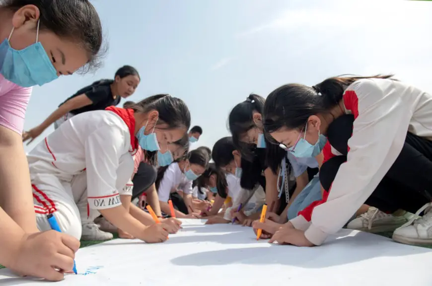 Photo taken on June 3, 2020, shows more than 60 primary school students in Chaohu city, east China’s Anhui province, signing their names on a 100-meter-long scroll to show their commitment to protecting the environment. (Photo by Li Yuanbo/People’s Daily Online)