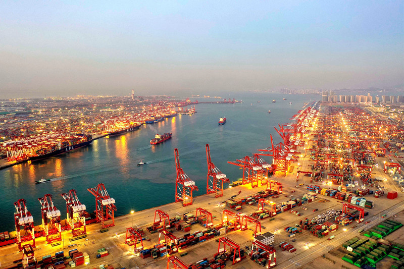 Photo taken on Nov. 9, 2020 shows cargos are being loaded onto and unloaded from container vessels at the brightly-lit Qianwan Container Terminal of Qingdao Port in east China’s Shandong Province. (Photo by Han Jiajun/People’s Daily Online)