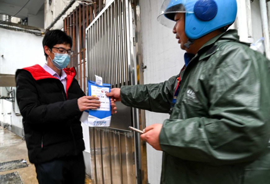 Photo taken on March 18 shows a delivery man handing medicine to a local resident in Jinhua, east China’s Zhejiang province at a door of the residential building where he lives. This year, Jinhua city has taken the lead in rolling out a service in its urban areas that allows enrollees of China’s basic medical insurance scheme to place orders for drugs from six pharmacies via online platforms like Alipay and make payments online with their medical insurance accounts. (Photo by Hu Xiaofei/People’s Daily Online)