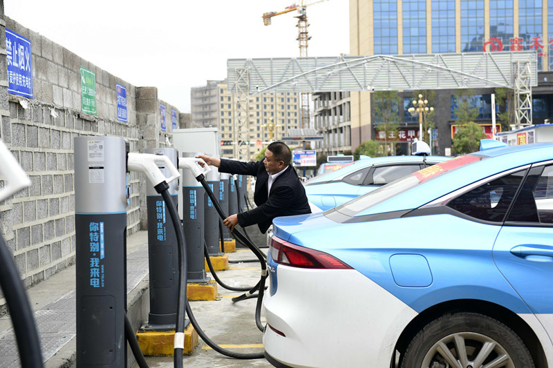 A driver charges up an electric taxi at a charging station in Anlong county, Qianxinan Buyi-Miao autonomous prefecture, southwest China's Guizhou province, March 10, 2021. (Photo by Liu Chaofu/People's Daily Online)