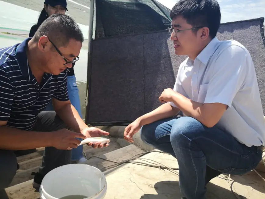 Wang Xujun, a fish farmer in Helan county, Yinchuan city, northwest China’s Ningxia Hui autonomous region, consults Jin Haoxuan, a teacher who specializes in water environment management in Tsinghua University, about technical matters in the middle stage of fish cultivation. (Photo/Ningxia Daily)