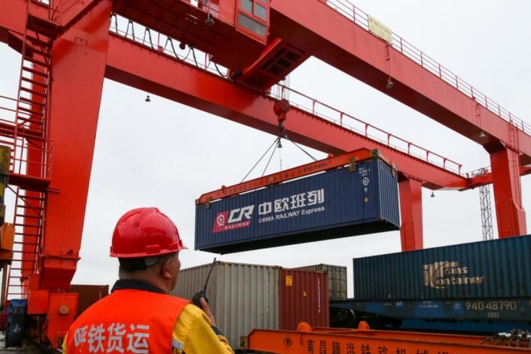 Photo taken on April 1, 2021, shows railway workers of the port of Erenhot in north China’s Inner Mongolia autonomous region having containers lifted onto a China-Europe freight train. (Photo by Xia Liang/People’s Daily Online)