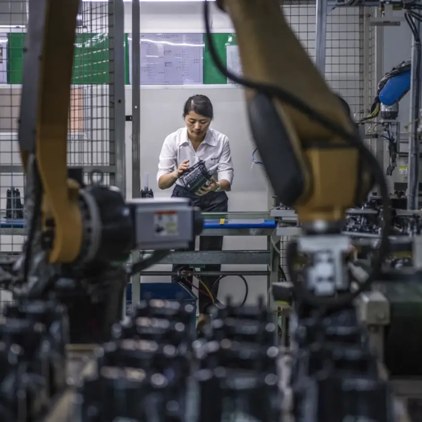 A worker conducts a spot check on electric coffee makers assembled by robots in a smart manufacturing shop of Guangdong Xinbao Electrical Appliances Holdings Co., Ltd., a company specializing in the development and manufacturing of home appliances, in south China’s Guangdong province, May 11, 2021. (Photo by Qiu Xinsheng/People’s Daily Online)