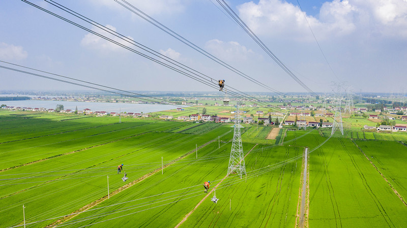 Workers at an electricity transmission and transformation subsidiary of State Grid Jiangsu Electric Power Co., Ltd. are busy installing devices at the construction site of a 500 kV power transmission and transformation project in east China’s Jiangsu province, August 25, 2021. Once completed, the project will increase the offshore wind power transmission capacity by about 6.4 million kWh and reduce carbon dioxide emissions by 17.6 million tons. (Photo by Shi Jun/People’s Daily Online)