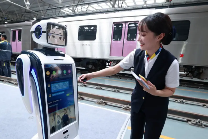 A subway attendant interacts with a robot to be put into service along Line 14 in Beijing, Sept. 15. (Photo by Chen Xiaogen/People’s Daily Online)
