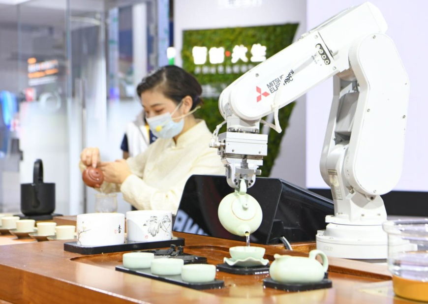 A robot and a tea master perform tea ceremony at the same time at the exhibition booth of Japan-based multinational Mitsubishi Electric at the 4th China International Import Expo (CIIE), Nov. 6, 2021. (Photo by Chen Bin/People’s Daily Online)