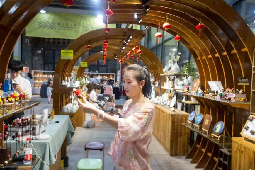 A livestreaming host promotes cultural and creative products at a night market of Taoxichuan Ceramic Art Revenue, a special zone for cultural and creative industries in Jingdezhen city, east China’s Jiangxi province. The zone was transformed from old state-owned ceramics factories. (Photo by Zhai Huiyong/People’s Daily Online)