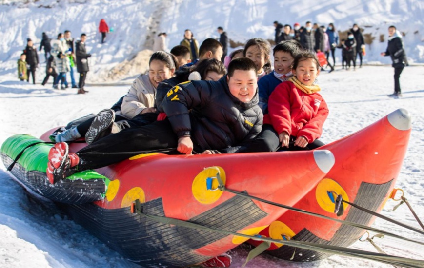 Children experience snow tubing on a banana boat at an ice and snow-themed park in Dakulun village, Hohhot city, north China’s Inner Mongolia autonomous region, Dec. 19, 2021. (Photo by Ding Genhou/People’s Daily Online)