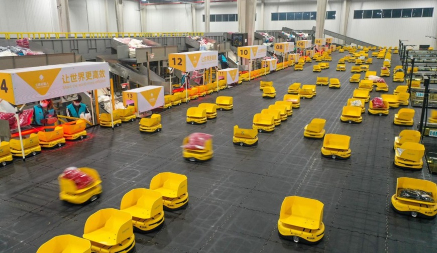 Workers assign parcels to robots at the logistics center of Fast Fish, a fast fashion retailer, in a smart logistics park in Deqing county, Huzhou city, east China’s Zhejiang province, Jan. 4, 2022. (Photo by Wang Shucheng/People’s Daily Online)