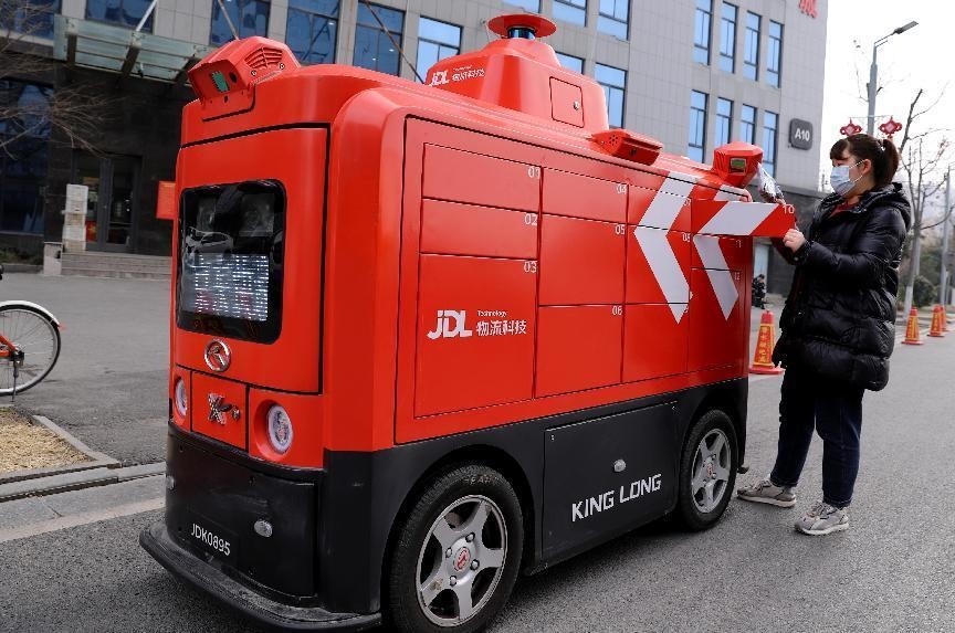 A woman collects her parcel from a smart courier vehicle in Suyu district, Suqian, east China’s Jiangsu province, Jan. 19, 2022. (Photo by Sun Dongcheng/People’s Daily Online)