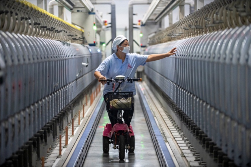 A worker inspects air jet looms in a workshop of a textile company in Lanxi city, east China’s Zhejiang province. (Photo by Hu Xiaofei/People’s Daily Online)