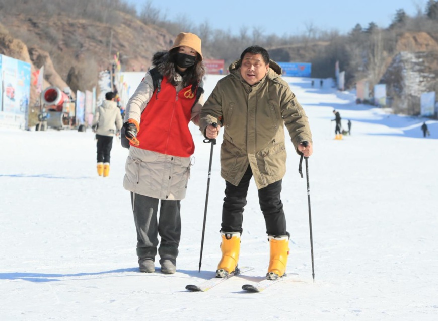 A person with disabilities learns to ski with the help of a volunteer in Chaoyang city, northeast China’s Liaoning province, Jan. 20, 2022. (Photo by Qiu Yijun/People’s Daily Online)