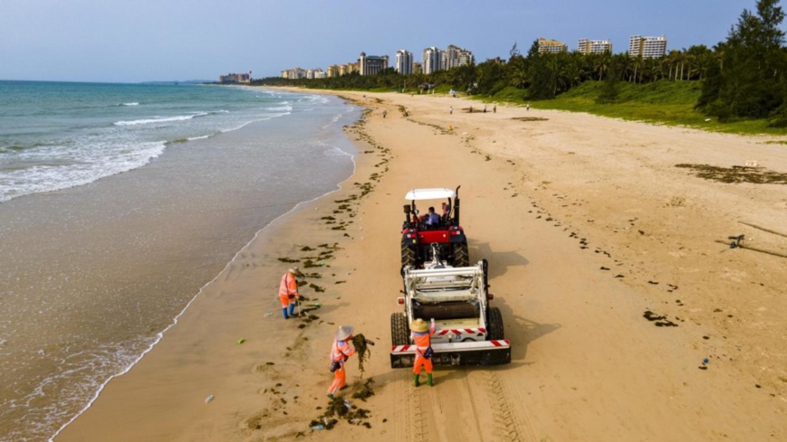 Sanitation workers clean a beach in Boao township, Qionghai, south China's Hainan province, April 13, 2022. (Photo by Meng Zhongde/People's Daily Online)