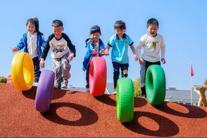 Photo taken on April 12, 2022 shows children of a kindergarten in Shuikou township, Changxing county, east China’s Zhejiang province in a tire rolling game. (Photo by Tan Yunfeng/People’s Daily Online)
