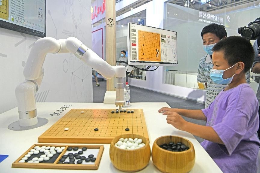 A boy plays Go with a robot developed by iFlytek, a Chinese information technology company at the 5th Digital China Summit and Exhibition, July 22, 2022. (Photo by Chen Bin/People's Daily Online)