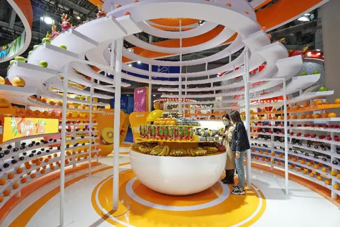 Visitors buy imported fruits at the food and agricultural products section of the fourth China International Import Expo, Nov. 7, 2021. (Photo by Tang Ke/People's Daily Online)