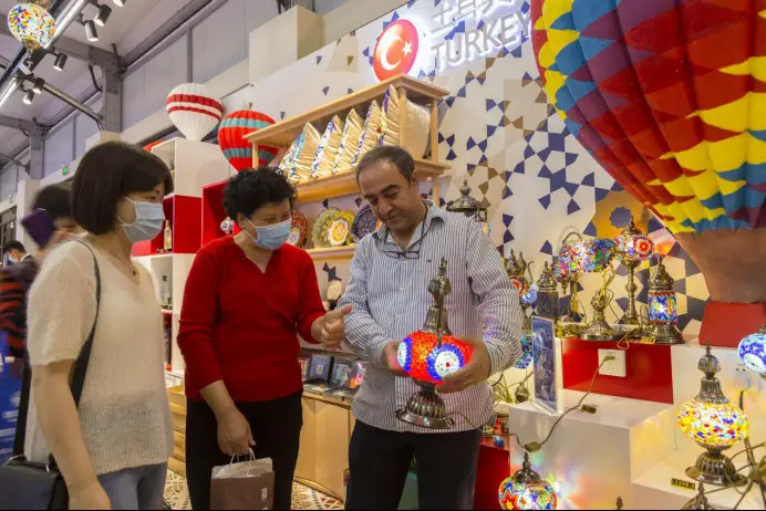 A man introduces a Turkish lamp to Chinese consumers at a commodity fair in Shanghai, May 1, 2021. The fair, opening on April 30, 2021, sells exhibits displayed at the China International Import Expo. (Photo by Wang Chu/People's Daily Online)