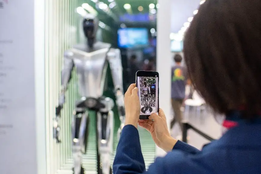A visitor takes photos of a humanoid robot developed by Tesla at the automobile exhibition section of the fifth China International Import Expo, Nov. 5, 2022. (Photo by Weng Qiyu/People's Daily Online)