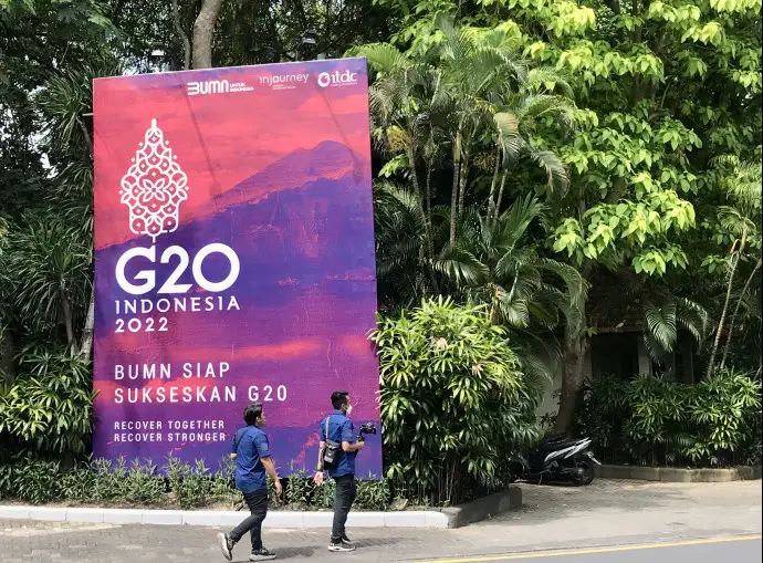 People walk past a banner with G20 logo in Bali, Indonesia, Nov. 13, 2022. (Photo by Yan Yunming/People's Daily)